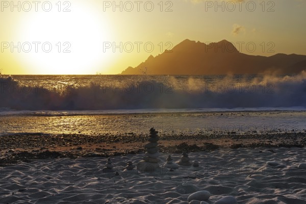 Land art in front of surf waves at sunset on Porto beach, Corsica