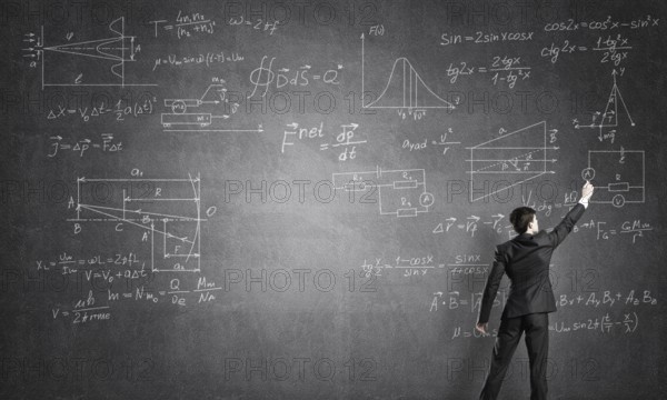 Man in suit standing with back and drawing formulas on chalkboard
