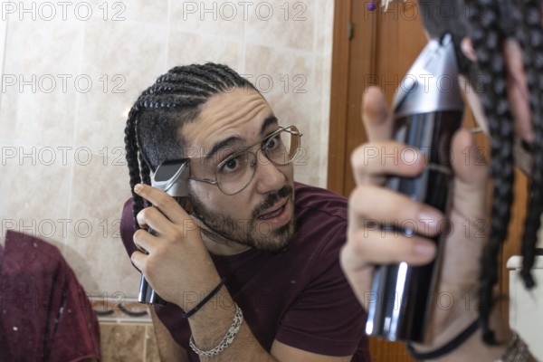 Guy in towel cutting his hair in front of mirror at home. Health Care Concept.