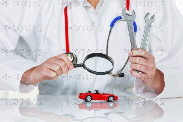 A model of a car is examined by a doctor. Symbol photo for workshop, service and car purchase. Austria