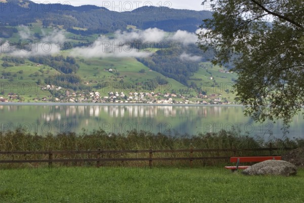 Wonderful lake in the Swiss Alpes, village and a red bench