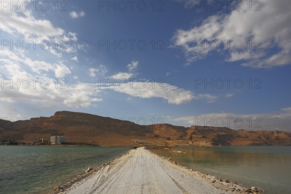 Sunset. Incredible lighting effects in a thunderstorm at the Dead Sea. The road in the middle of the sea