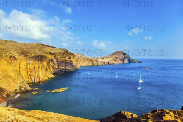 The west coast of Madeira - the bay between the rocks with yachts and boats. Madeira is island in the Atlantic. The blinding midday sun. The concept of active, ecological and photo tourism