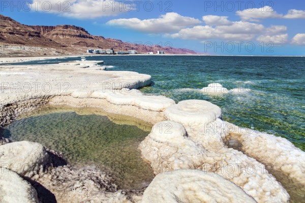 Evaporated salt forms crystals on the surface of the water. The saltiest lake in the world. Dead Sea. Israeli coast, warm winter February day. The drainless salt lake in the Middle East