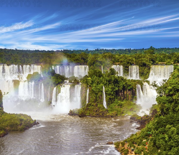 Several waterfalls from Iguazu Falls. Powerful two-stage waterfall creates rainbow and watery dust. The concept of exotic and extreme tourism