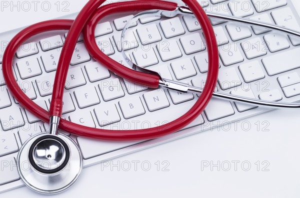 Image shows a red stethoscope at a computer keyboard