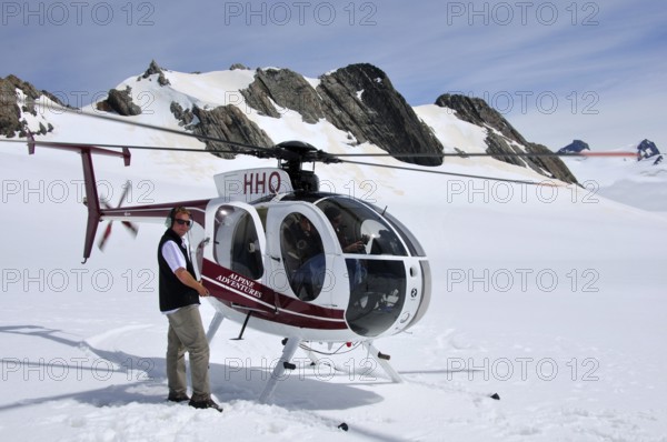 FRANZ JOSEF GLACIER, NEW ZEALAND: DECEMBER 24, 2009: Pilot welcomes passengers aboard his helicopter on the snow above Franz Josef Glacier, Westland, New Zealand