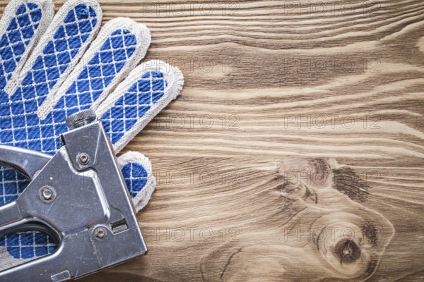 Set of staple gun protective gloves on wooden board