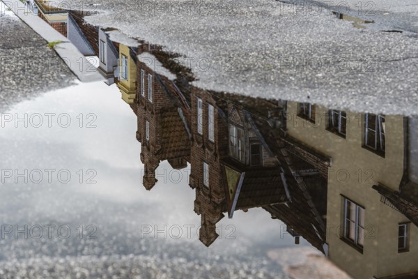 Reflection on water puddle of colorful old gable houses in historic centre of Lubeck, Germany