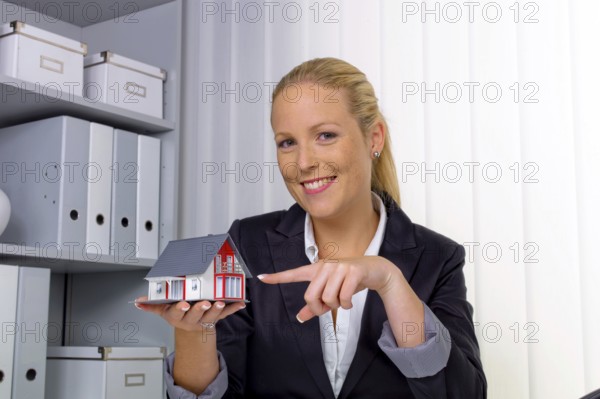 A young property agent with a model house in her office. Austria