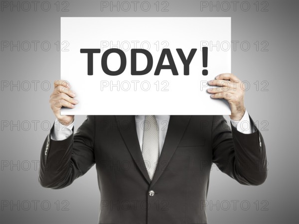 A business man holding a paper in front of his face with the message today