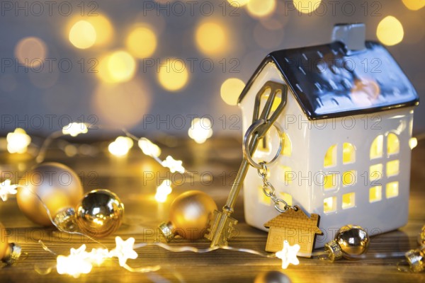 Key to the house with a keychain on a lamp with a Christmas decor. A gift for New Year, Christmas. Building, design, project, moving to new house, mortgage, rent and purchase real estate. Copy space