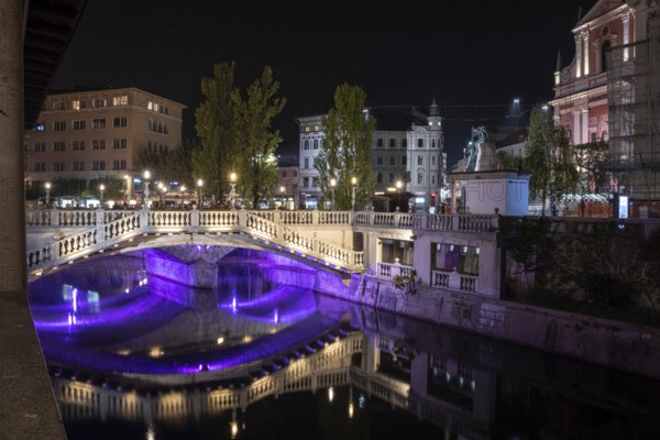 Famous three bridges at the Preseren square in the center of Ljubljana colorfully illuminated at night, Slovenia