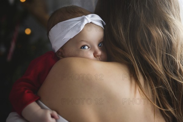 Mother holding cute newborn baby girl in her arms. Sleepy baby yawning
