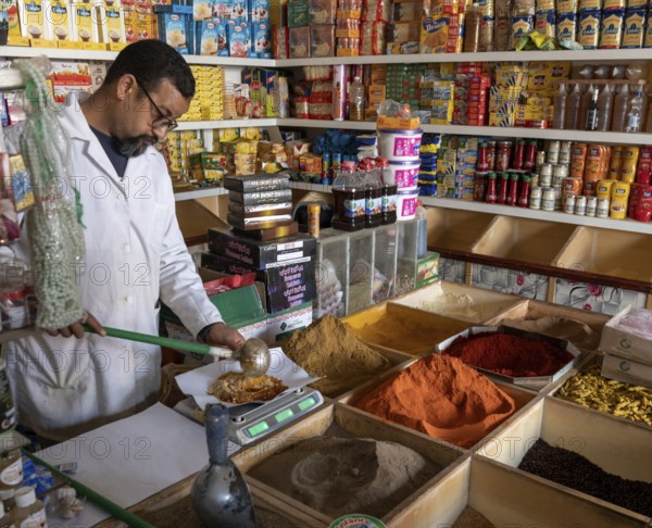 Er-Rich, Morocco, 7 March, 2024: Moroccan shopkeeper mixing spices in his shop in the market of Er-Rich
