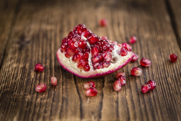 Pomegranate on an old wooden table as detailed close-up shot (selective focus)