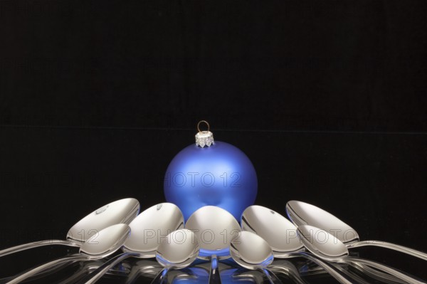 Blue Christmas decoration and nine spoons on a black glass desk
