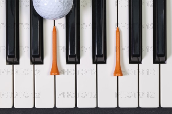 Virtuosic game - Piano keyboard and different golf balls and wooden tees