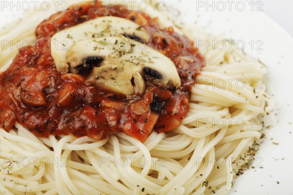 Spaghetti with tomato souce and champignons on white plate