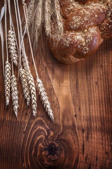Loaf of breead and wheat ears on vintage wooden board with small copyspace food and drink concept