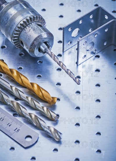 Perforated angle fasteners metal ruler drill and bits on metallic background construction concept