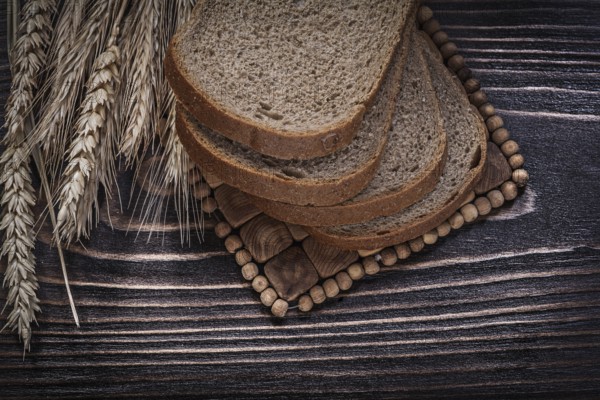 Golden rye wheat ears sliced loaf of bread wicker mat food and drink concept