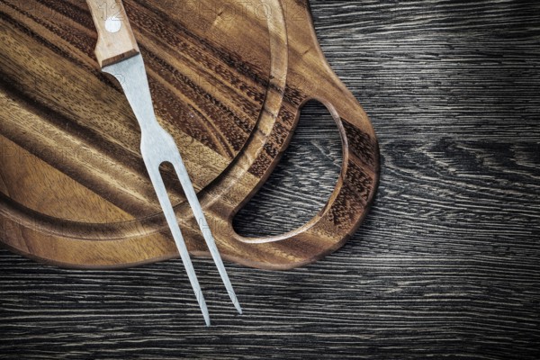 Meat fork cutting board on wood background