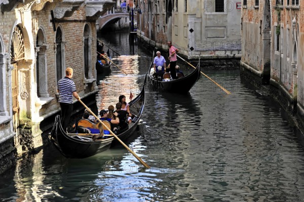 Venice, Veneto, Italy, Europe, Tourists enjoy a gondola ride through the narrow canals between historic buildings