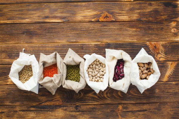 Textile bags with natural cereal food on wooden table, copy space, top view