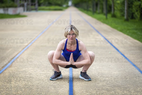 Woman stretching hips and adductors in a squat position, Belgium