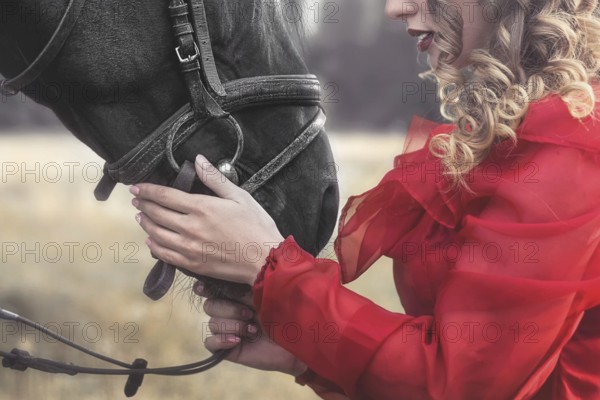 Love for animals. young Woman with no face dressed in an elegant vintage dress, gently cuddling a horse, stroking his head