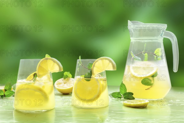 Lemonade with mint on a green background. Lemon water drink with ice. Two glasses and a pitcher. Detox beverage. Fresh homemade cocktail, Food photography, Food photography