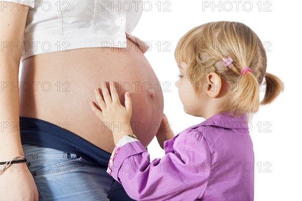 Daughter hugging mother's pregnant belly isolated on white