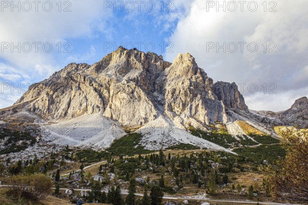 The majestic pass in the Eastern Alps of Falzarego. Picturesque sunset in the colorful rocks of the Dolomites. White and gray dolomite rocks. The clouds are flying across the sky