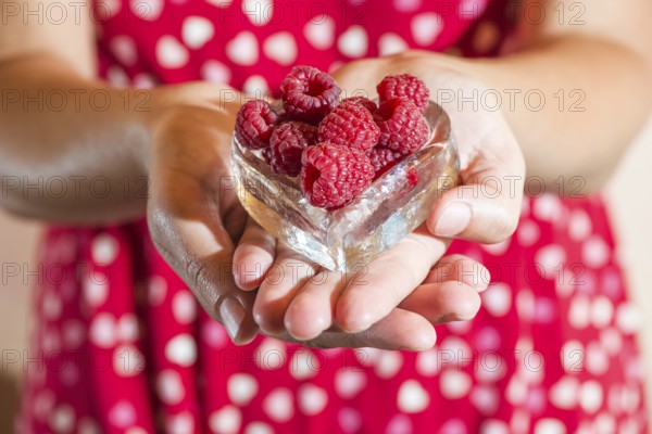 Woman in red dress holding a cup of raspberries