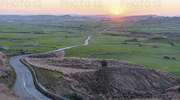 Empty curvy asphalt rural road through farmland filed at sunrise. New day outdoor nature