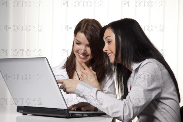 Young girls learn and work together on a laptop