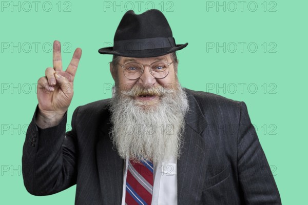 Portrait of happy bearded man showing victory sign. Isolated on green