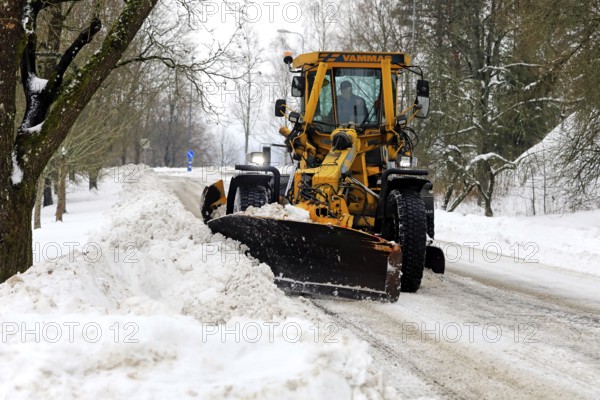 Yellow motor grader Vammas removing snow from street after heavy snowfall in Salo, Finland. January 22, 2021