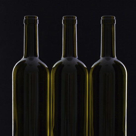 Three different bottles of wine on the black glass