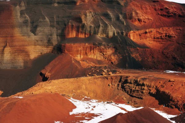 Martian landscapes in Iceland. The red crater of The Seydisholar volcano. The quarry of red soil mining. White snow lies on red soil