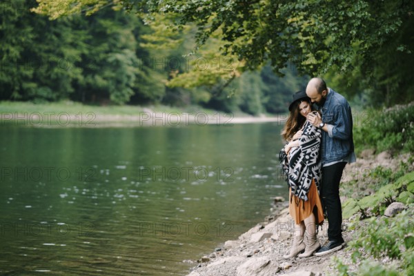 Man hugs a pregnant woman by the lake.