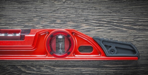 Red construction level on wooden board top view