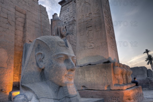 Illuminated entrance of Luxor temple with Ramses II statue and obelisk, Luxor, Egypt