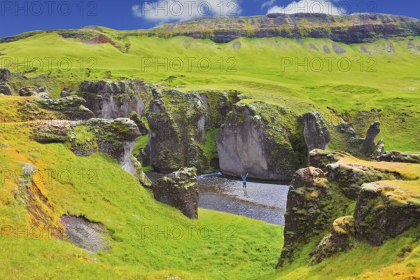 Enthusiastic woman - tourist on a rock canyon Fjadrargljufur. Fantastic country Iceland