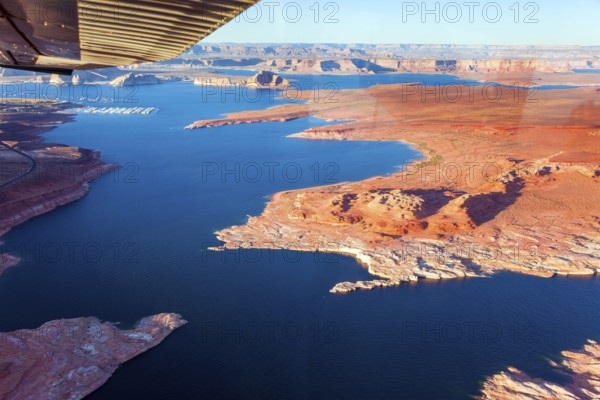 Landscape under the wing of an airplane. Lake Powell is a reservoir on the Colorado River located in the U.S. The blue water of the lake contrast with the red-brown massifs of the rocks