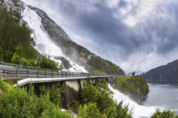 The cascading powerful Langfossen waterfall intersects with the highway and flows into the Acre Fjord. Western Norway. Majestic natural phenomenon. Unique wonder of nature