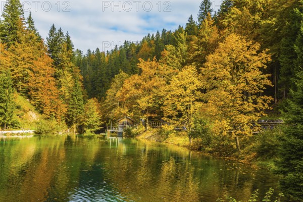 Fantastically beautiful autumn forests are reflected in the quiet lake Lago de Fusine. Easy ripples on the lake. Flood after rain. Concept of cultural and ecological tourism