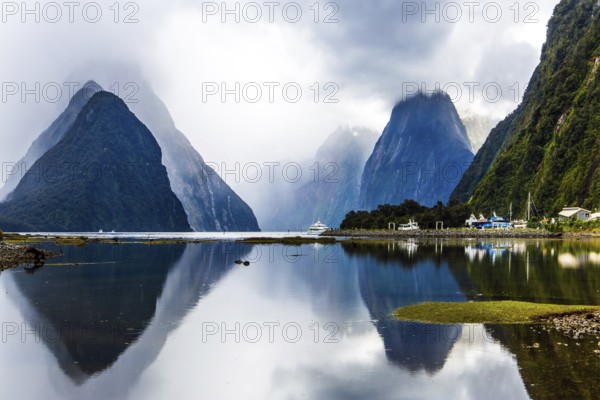 Land of hobbits - New Zealand. Port of tourist and pleasure ships, yachts and boats. Storm clouds cover the sky over the ocean fjord Milford Sound. Concept of exotic, ecological and photographic tourism
