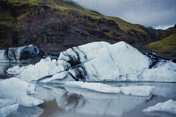 Ice formations near mountains reflecting in calm water under a cloudy sky, iceberg, glacier, snow, ice rock, ice diamont, glacier lagoon, nature, snow, Iceland